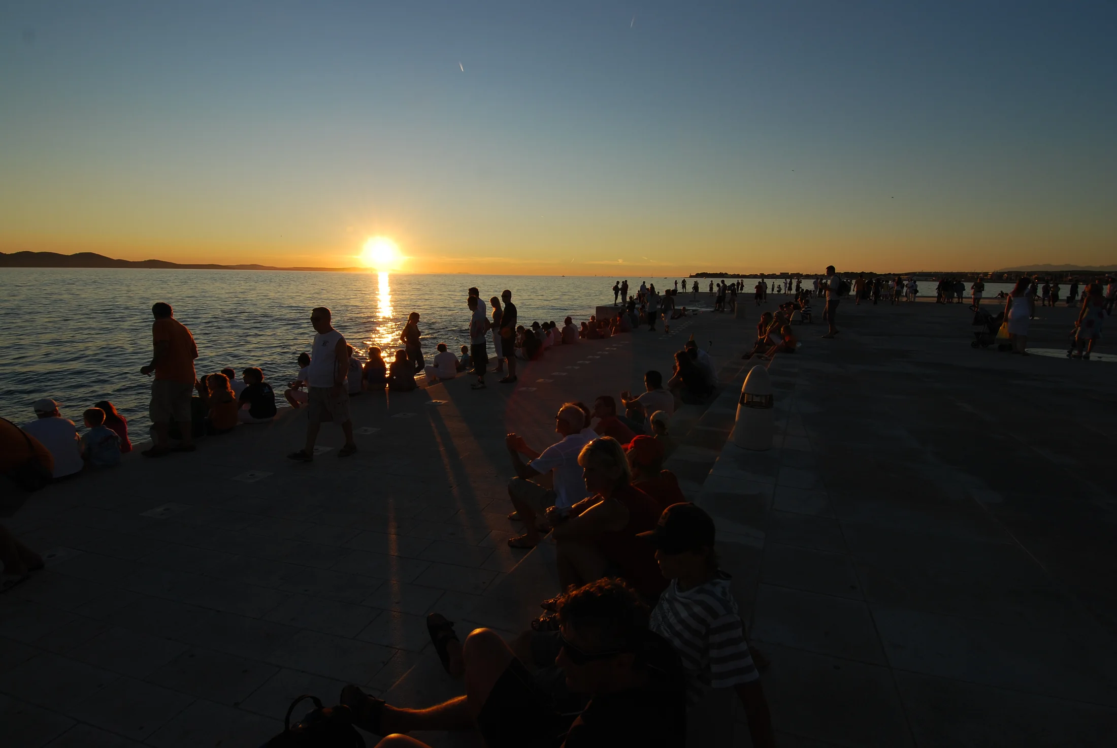Golden sunset over the Adriatic with visitors listening on the Sea Organ steps in Zadar